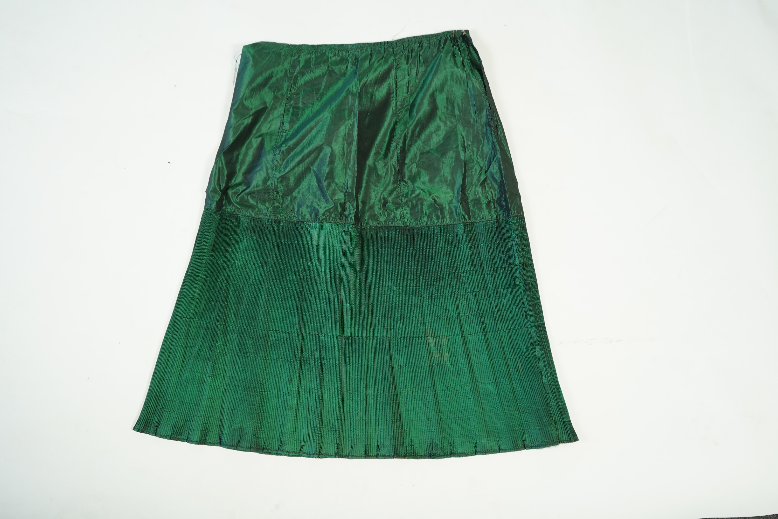 A flesh coloured 1930s lace evening dress and matching jacket together with a bottle green velvet evening dress and buckle belt and an unusual green shot silk pleated under skirt. Lace dress bust 32 inches. 156cm long. C